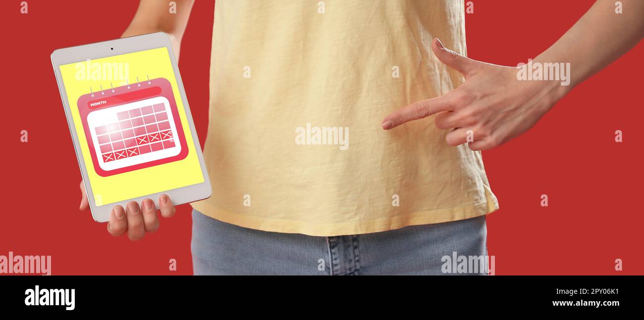 Young woman holding tablet computer with open menstrual calendar on ...