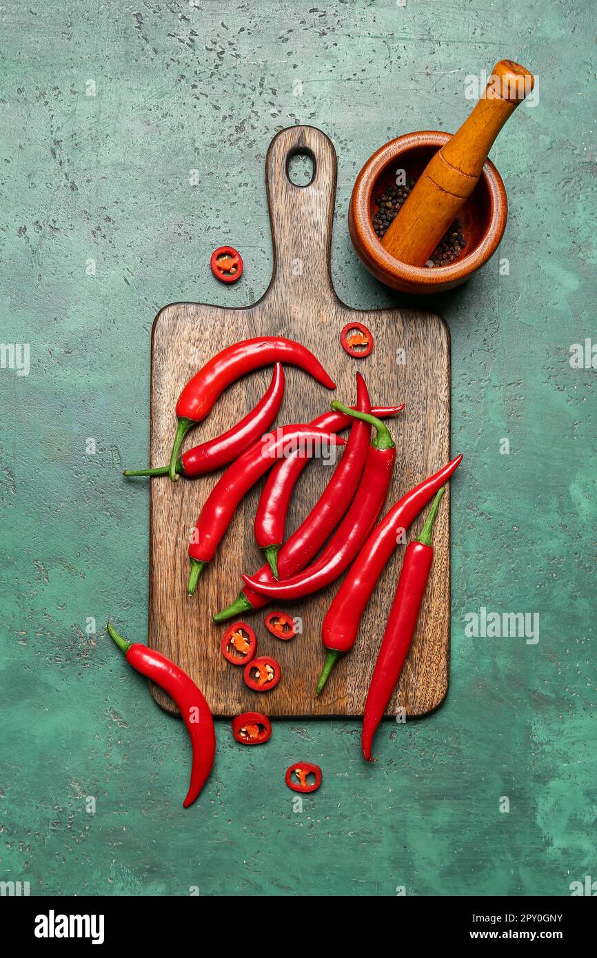 Wooden board with fresh chili peppers on green background Stock Photo ...