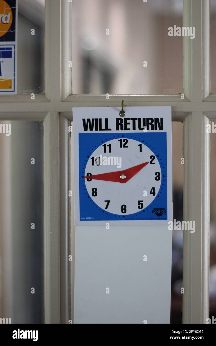 'WILL RETURN' clock on the door of an office letting patrons know when they will return. Sometimes they don't! Stock Photo