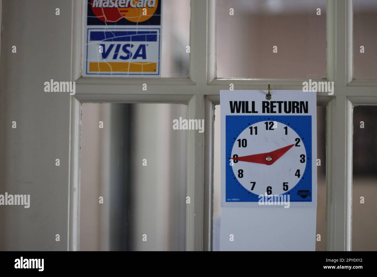 'WILL RETURN' clock on the door of an office letting patrons know when they will return. Sometimes they don't! Stock Photo