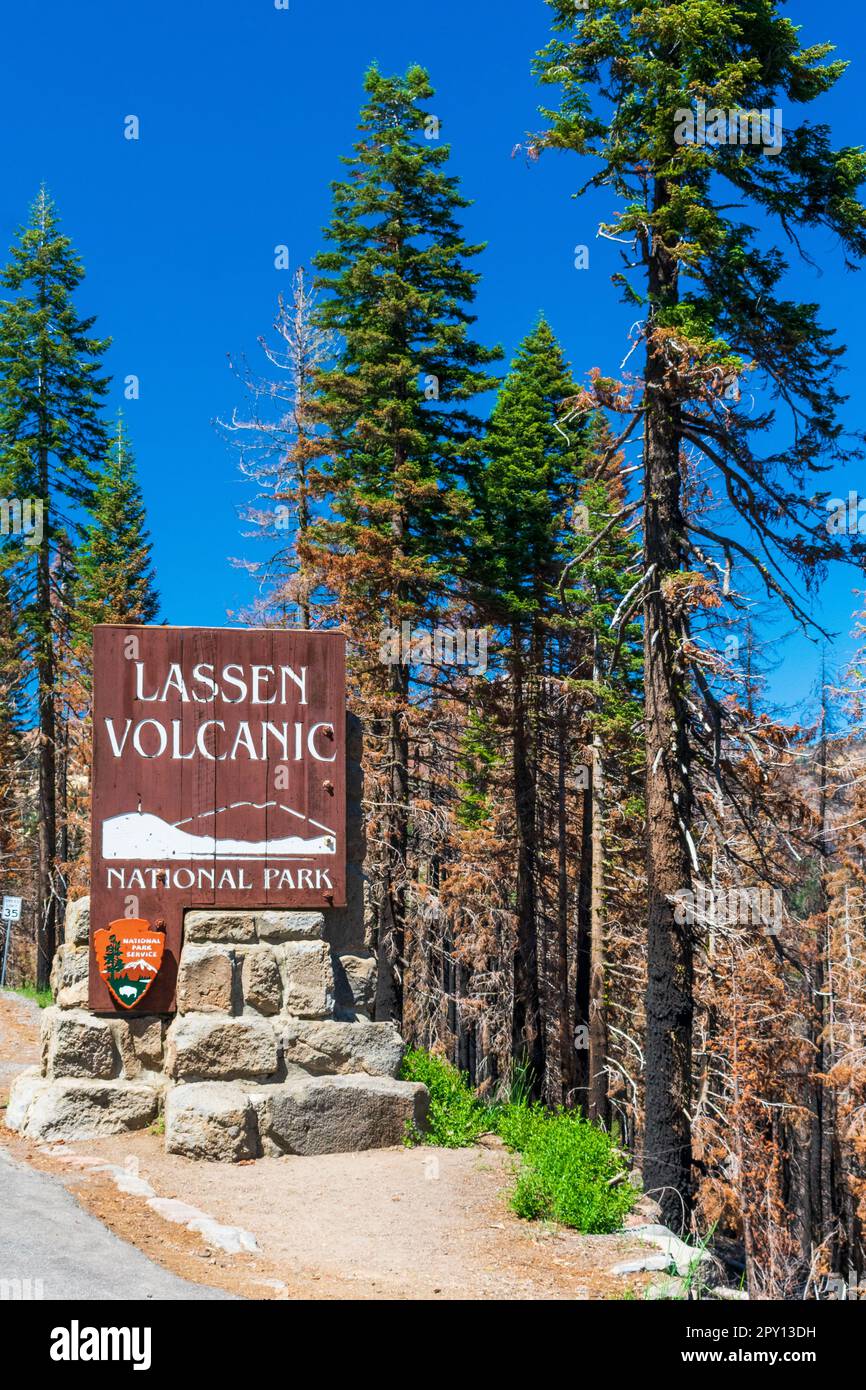 Lassen Volcanic National Park, CA / USA - 29 JUN 2022: Entrance sign for Lassen Volcanic National Park, California seen with trees burned form wildfir Stock Photo