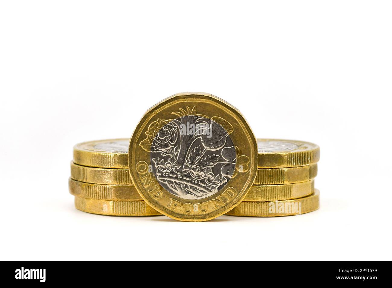 British one pound coin standing on its edge with other coins isolated aganst a plain white background. Copy space. Stock Photo