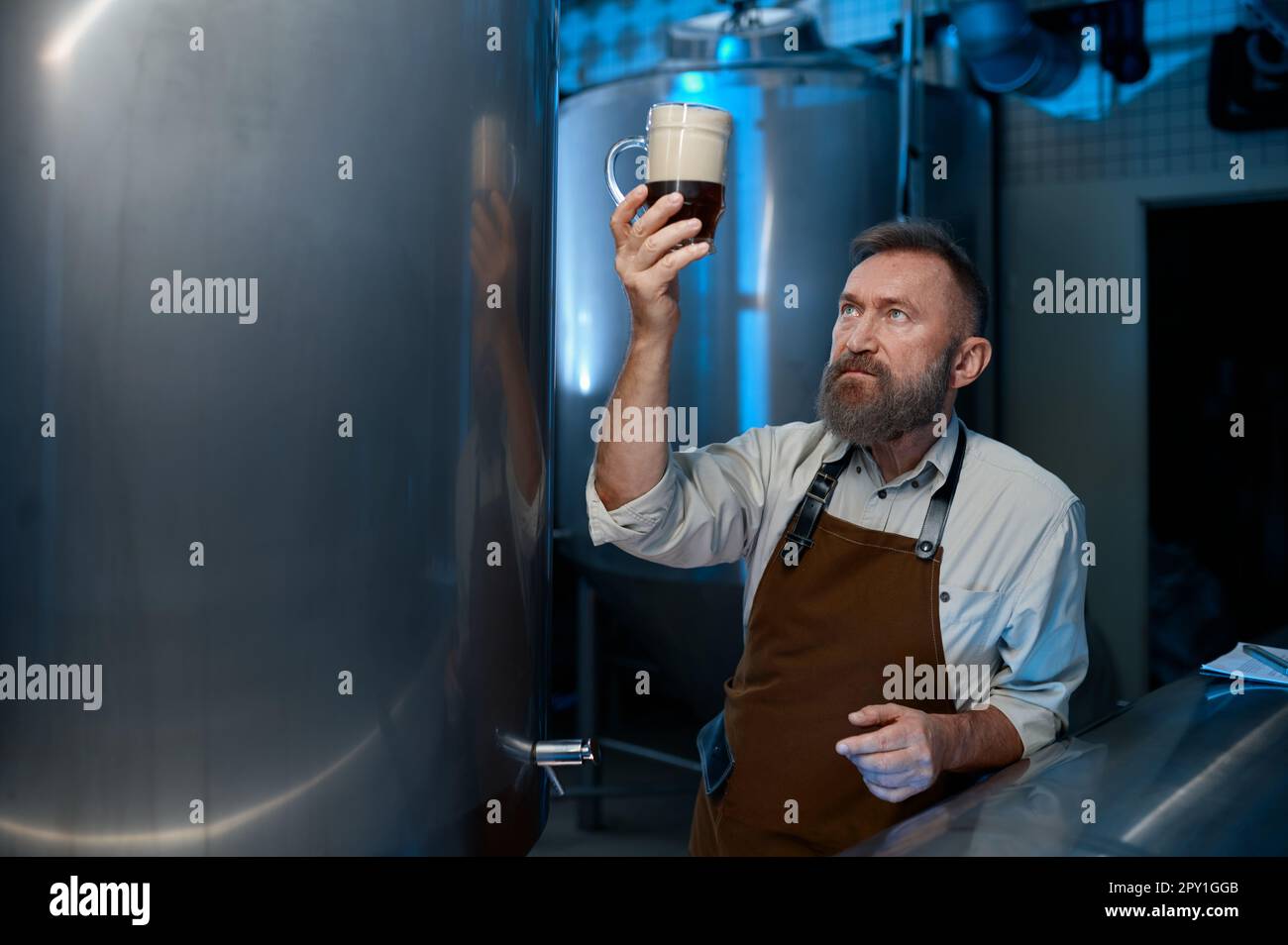 Bearded senior brewer checking beer quality during brewing technology