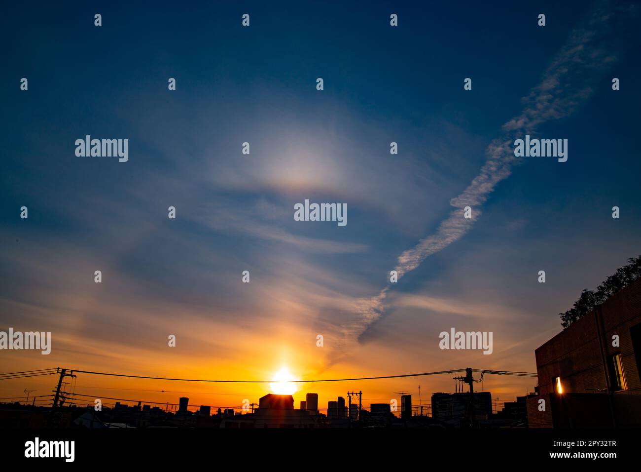 A view of the sunrise in Tokyo. An early morning in a residential area. There are silhouette of tall sky scrappers at far distance. Stock Photo