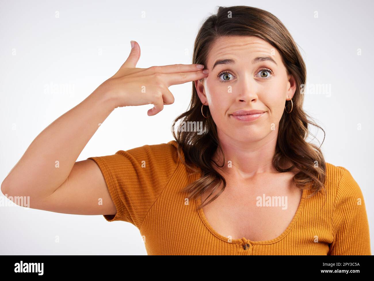 How I feel after a day at work. Studio shot of a young woman making a gun with her hands against a white background. Stock Photo