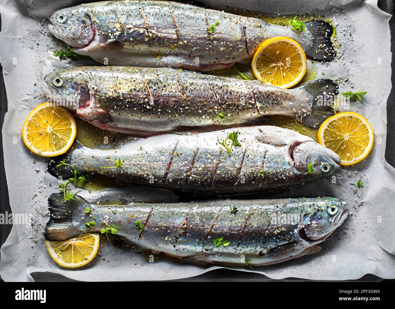 Fresh rainbow trouts with salt, lemon and herbs ingredients. Tasty fishes preparing for dish lunch. Stock Photo