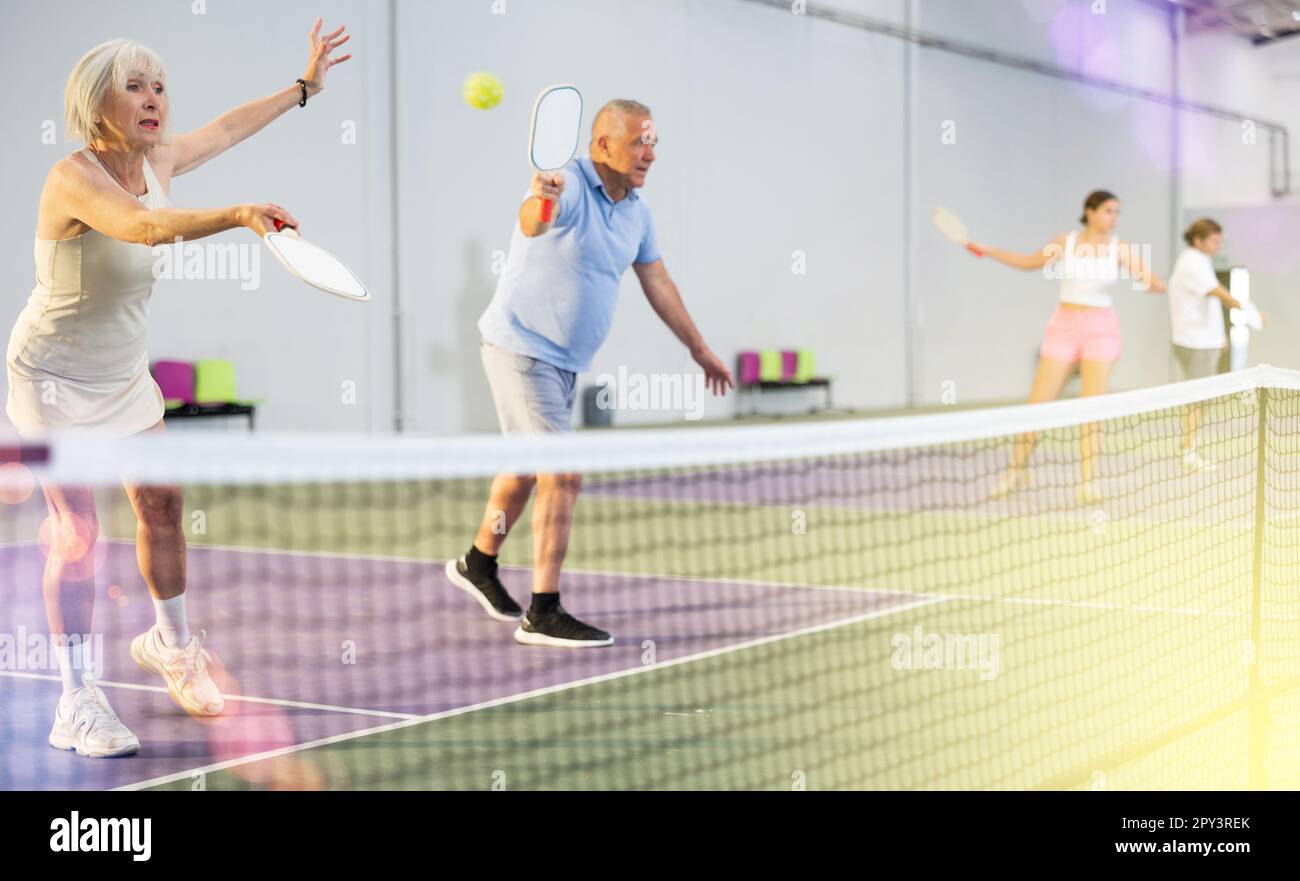 Athletic seniors playing pickleball on court indoors Stock Photo Alamy