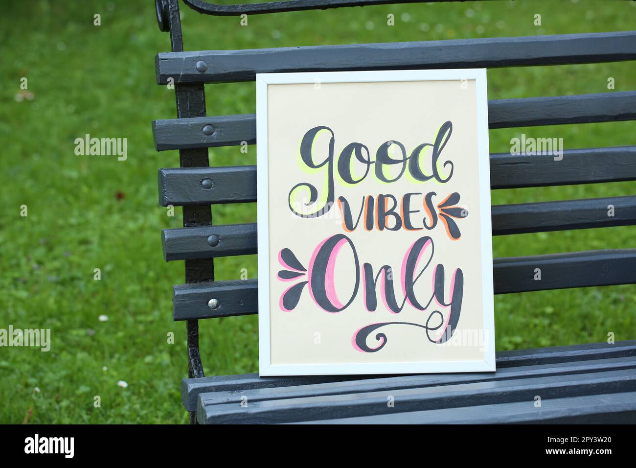 Poster with phrase Good Vibes Only on black wooden bench outdoors Stock Photo