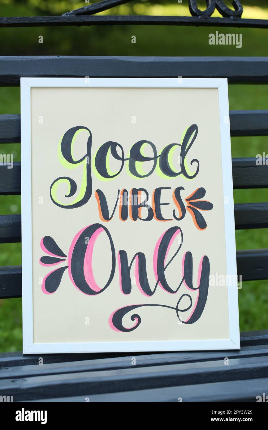 Poster with phrase Good Vibes Only on black wooden bench outdoors Stock Photo