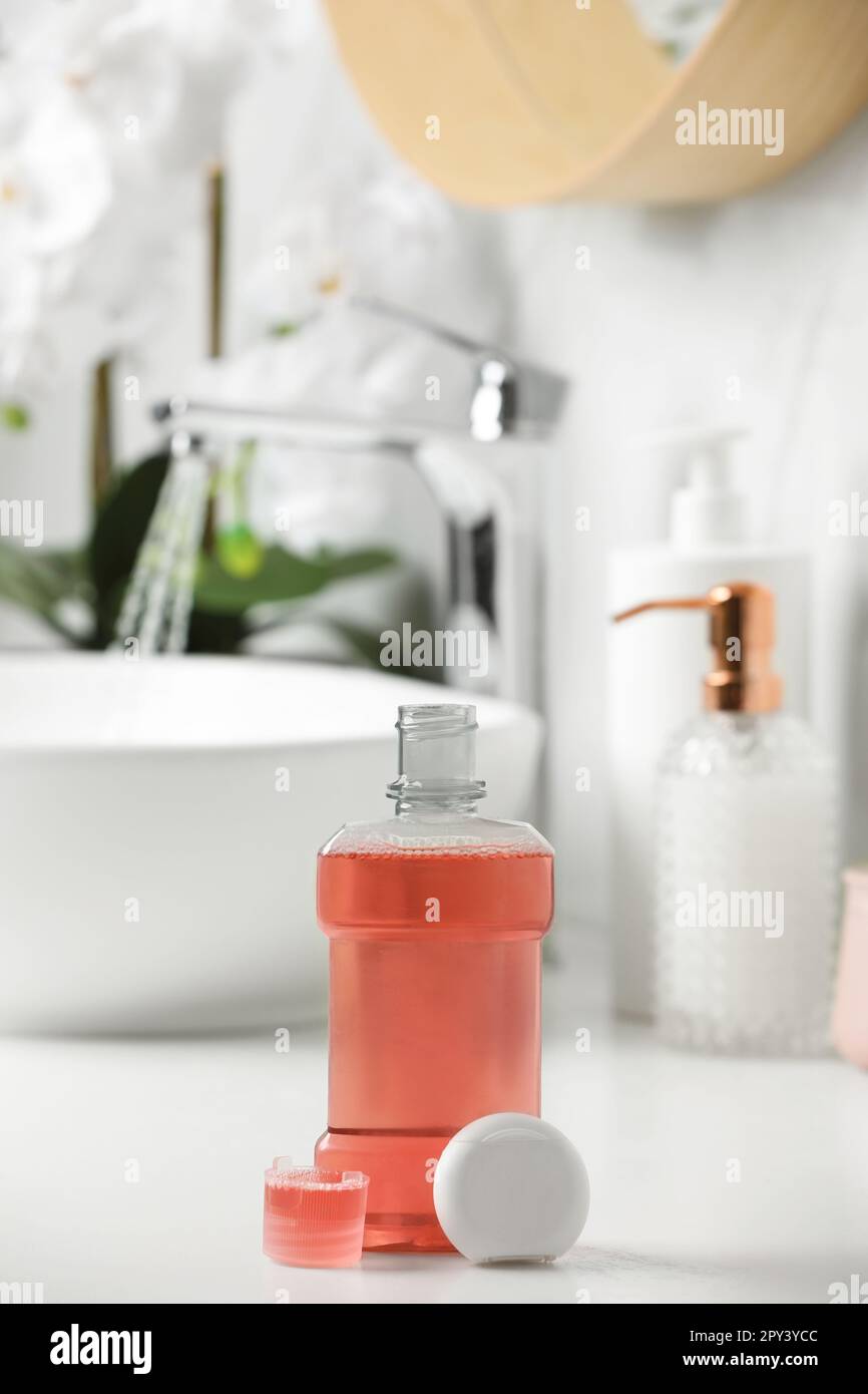 Mouthwash and dental floss on white countertop in bathroom Stock Photo
