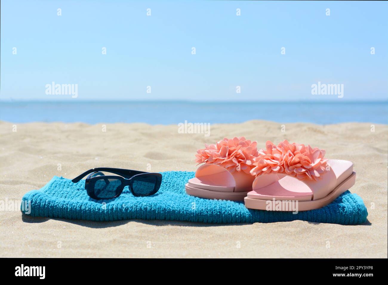 Towel, flip flops and sunglasses on sand near sea. Beach accessories ...