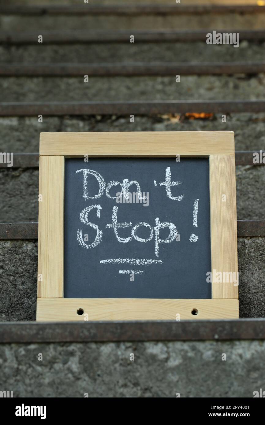 Chalkboard with phrase Don't Stop on stone stairs outdoors Stock Photo