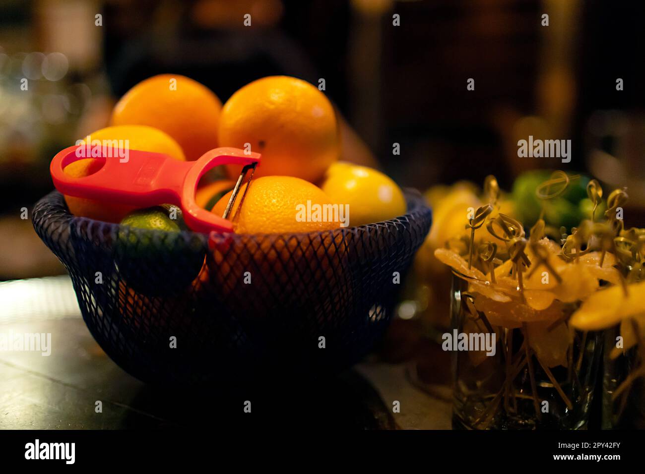 Black bowl of citrus fruits with peeler and cocktail garnishes Stock