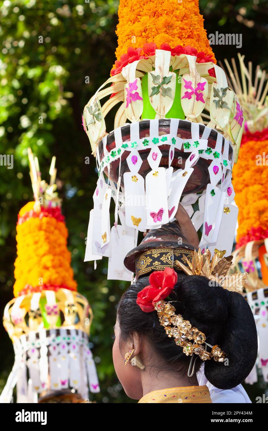 Procession of beautiful Balinese women in traditional costumes - sarong, carry offering on heads for Hindu ceremony. Arts festival, culture of Bali is Stock Photo