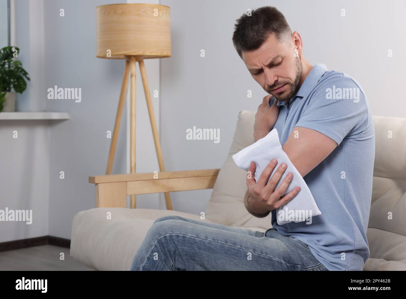 Man using heating pad at home, space for text Stock Photo Alamy