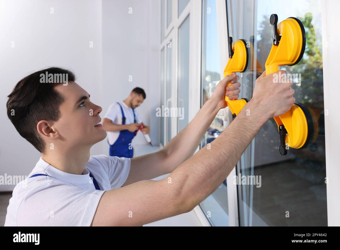 Worker using suction lifters during plastic window installation indoors Stock Photo