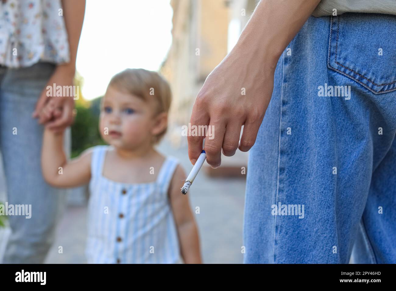Woman smoking cigarette in public place outdoors, closeup. Don't smoke