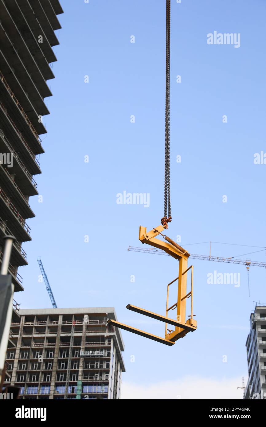 Tower crane near unfinished buildings against cloudy sky on