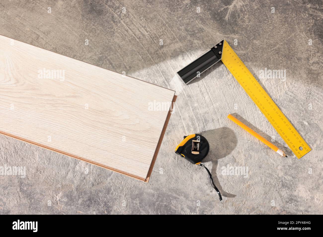 Parquet plank, measuring tape, pencil and ruler on floor, flat lay ...