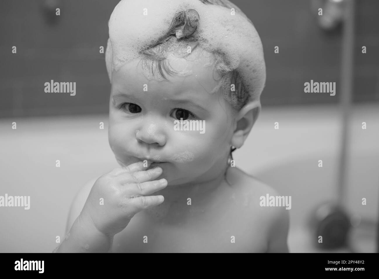 Baby child washing in a bathroom in foam. Funny kids face close up. Kid