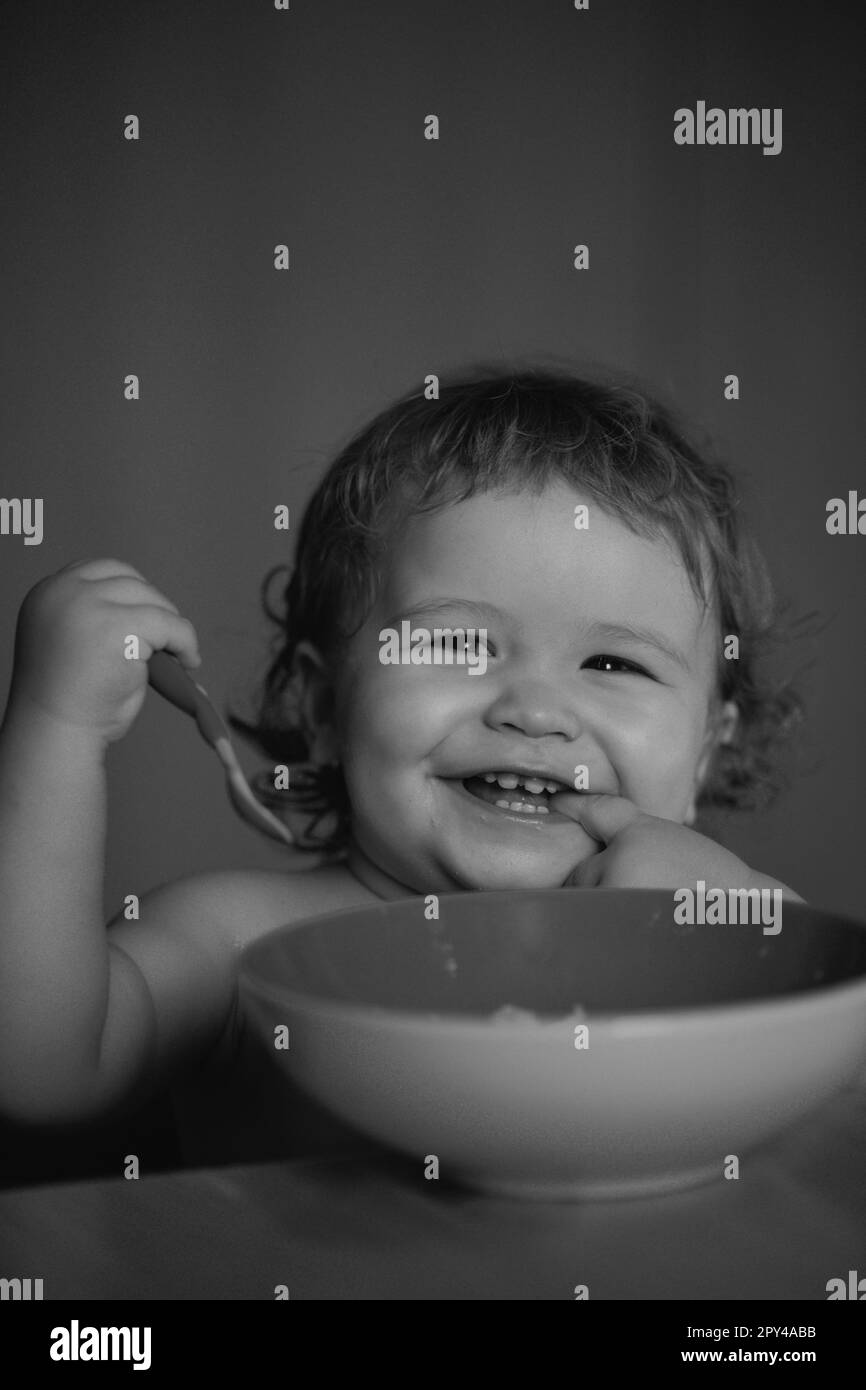 Kid baby eat soup in the kitchen with dishes and spoon. Launching child ...