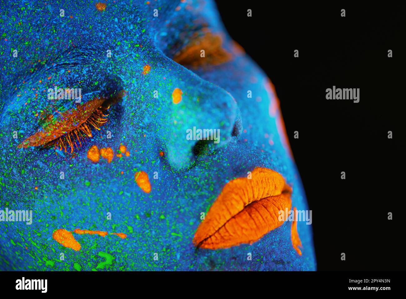 Neon paint, makeup and woman face closeup with dark background and