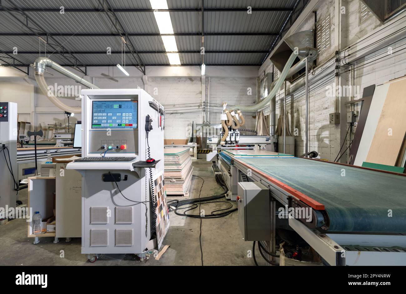 Atmosphere inside wooden furniture factory with piles of plywood and modern machinery,  controlled by computer system. Stock Photo