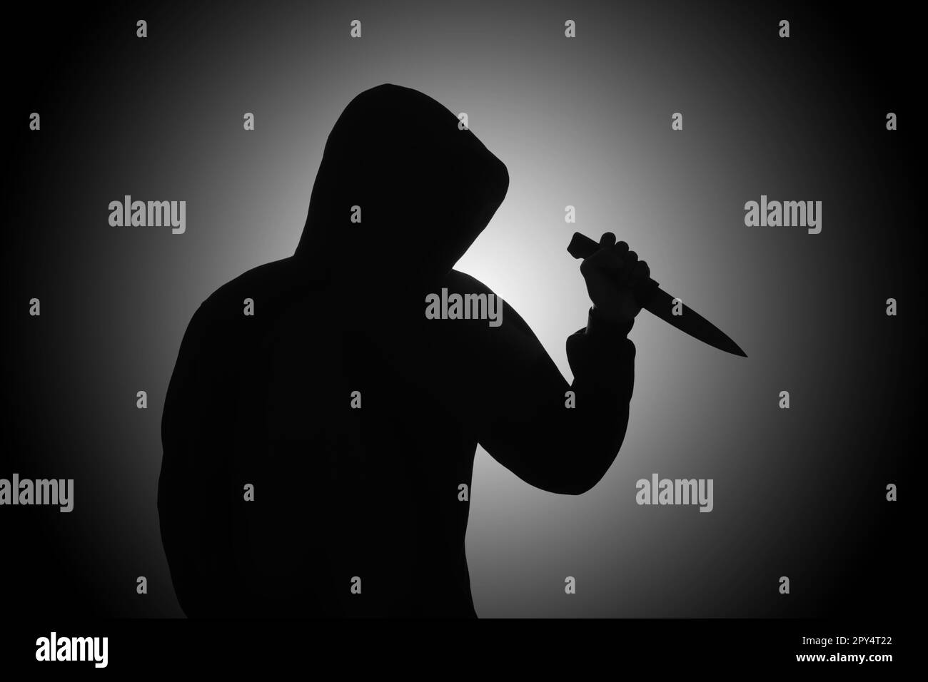 Mysterious man wearing black hoodie holding a knife to stab someone. Crimes and criminality concept Stock Photo