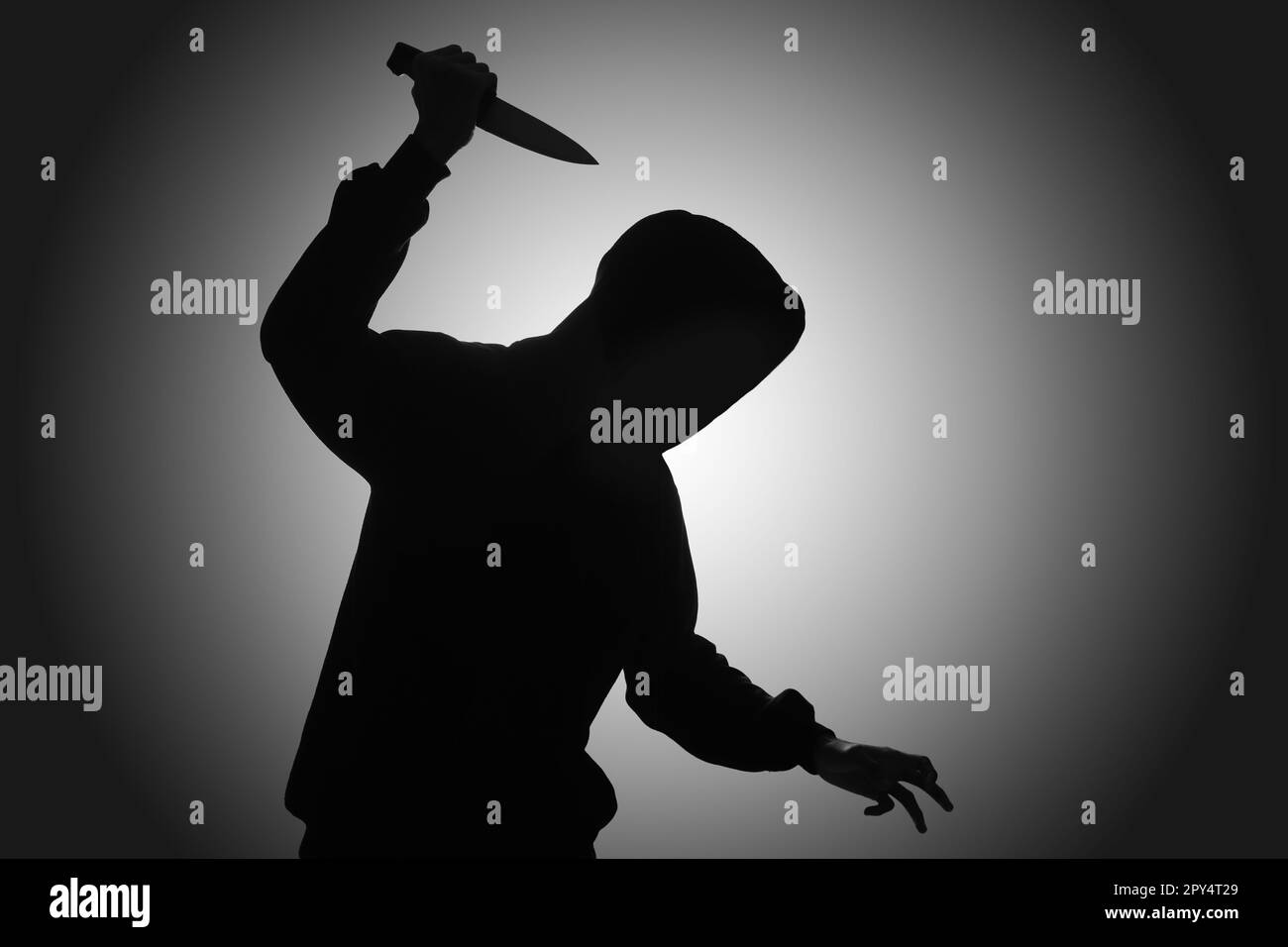 Mysterious man wearing black hoodie holding a knife to stab someone. Crimes and criminality concept Stock Photo