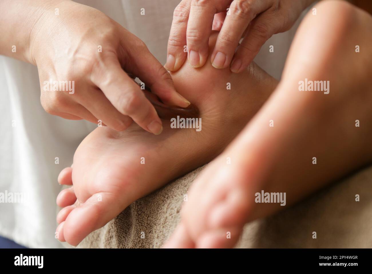 Client receiving acupressure reflexology treatment with wooden points massager stick. Natural medicine, reflexology, acupressure foot massage Stock Photo