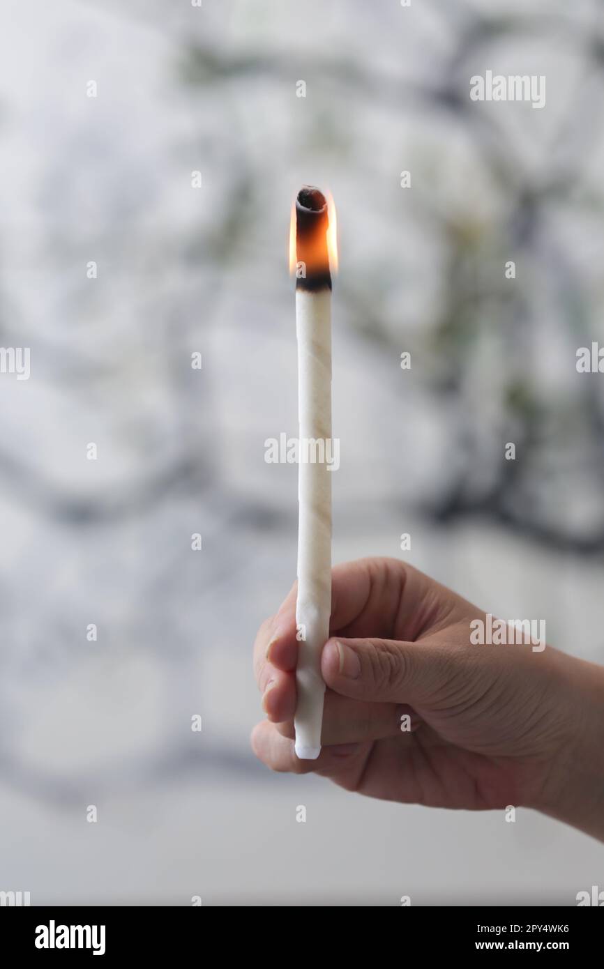 Woman holds lighted ear wax candle. Ear wax removal method Stock Photo