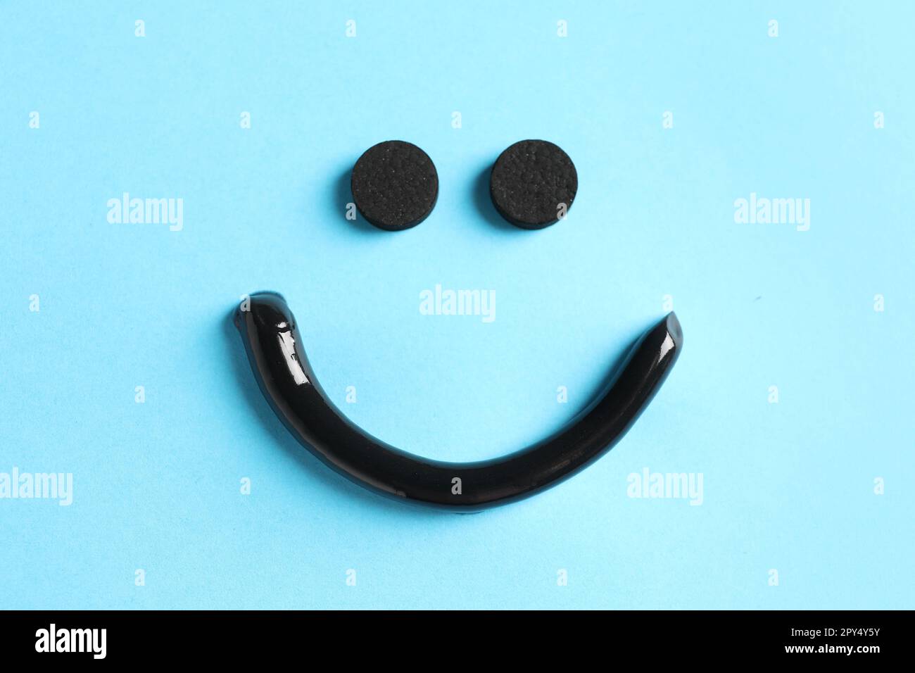 Smile made from charcoal toothpaste and tablets on light blue ...