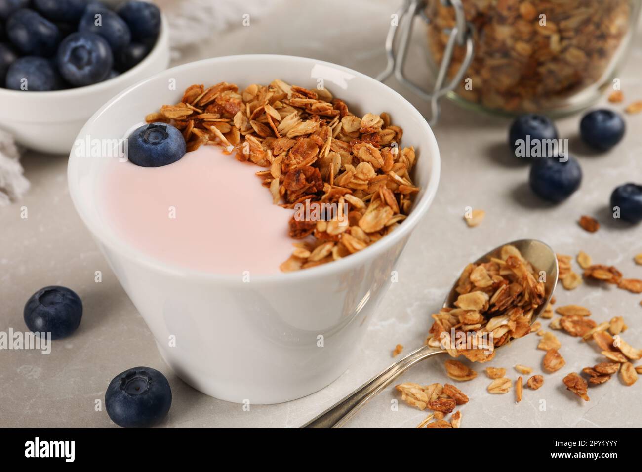 Delicious yogurt with granola and blueberries served on grey marble table, closeup Stock Photo