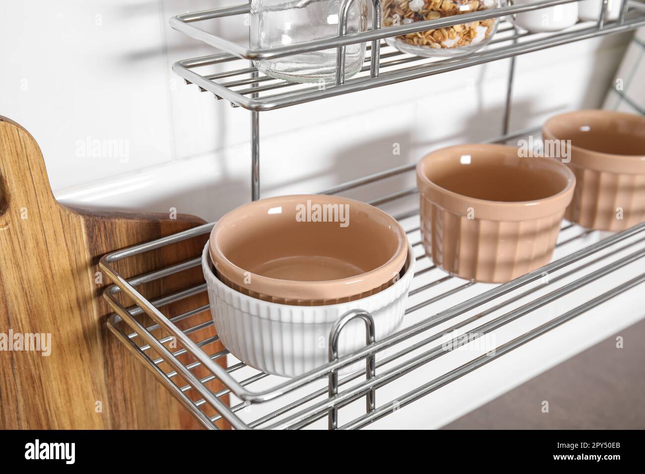 Many different ramekins on metal rack in kitchen Stock Photo