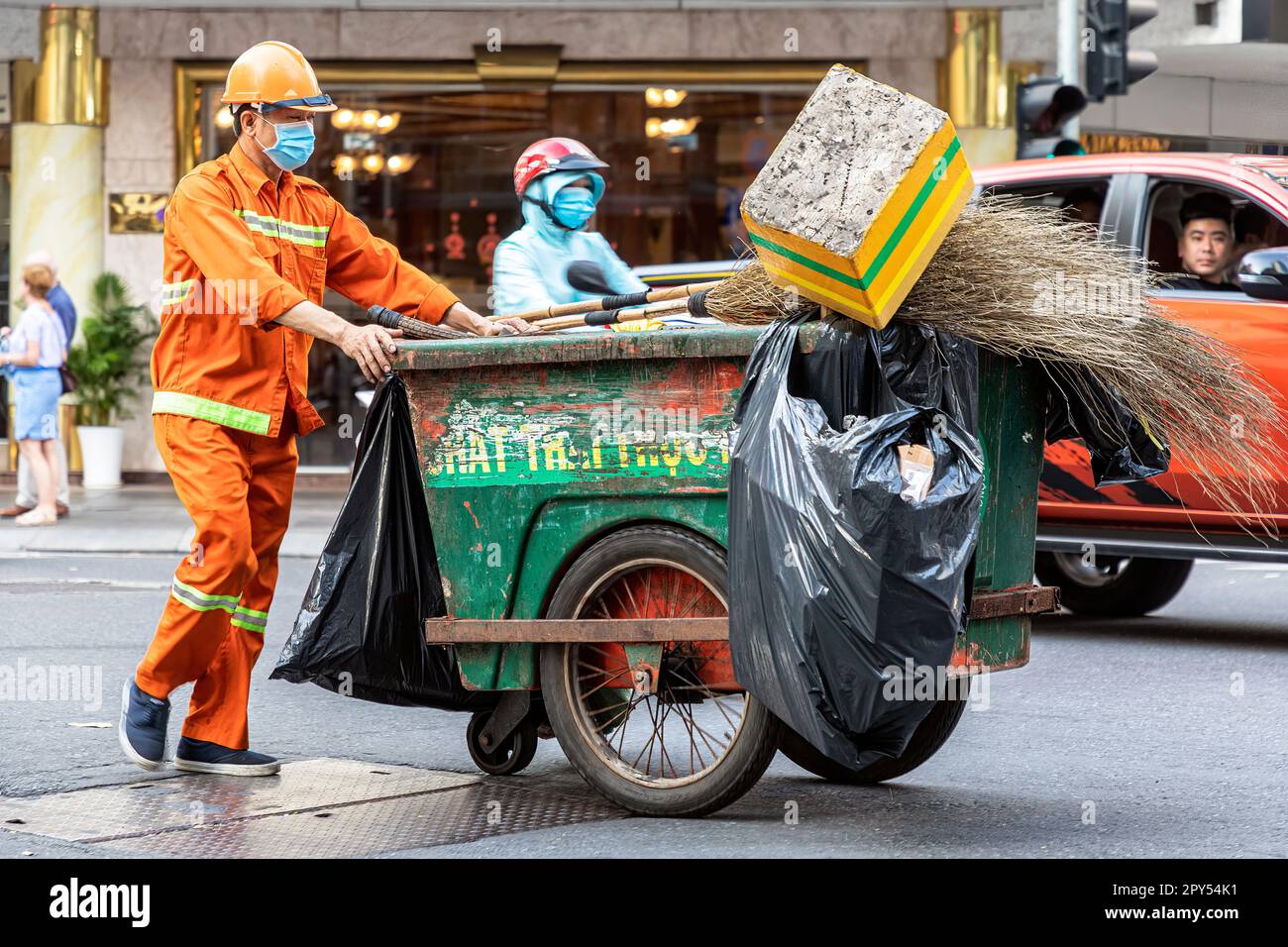 Garbage collector wearing high visibility clothing with pushcart on