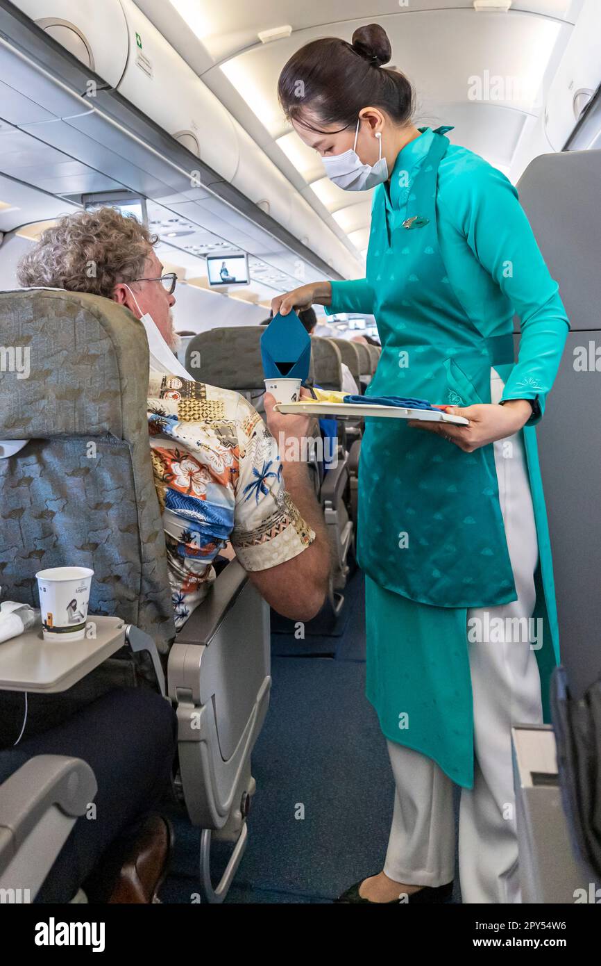 Vietnam Airlines cabin crew taking care of passengers, wearing ao dai