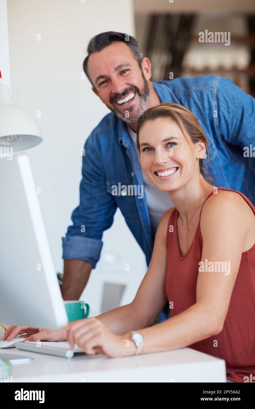 Im lucky to have such marital support. Portrait of an attractive young woman sitting on a computer with her husband standing beside her. Stock Photo