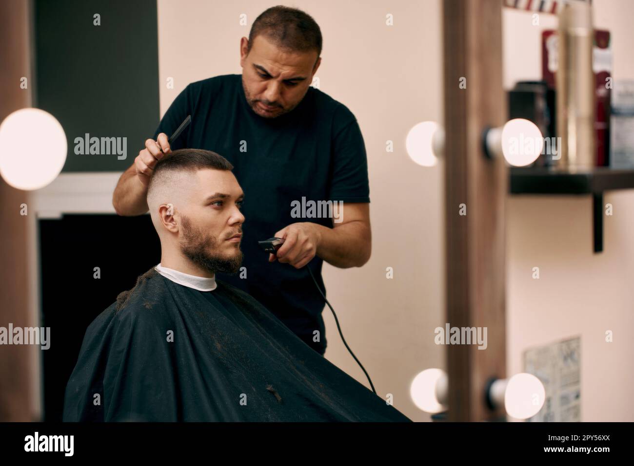 hairdresser does hairstyle with scissors in barber shop Stock Photo