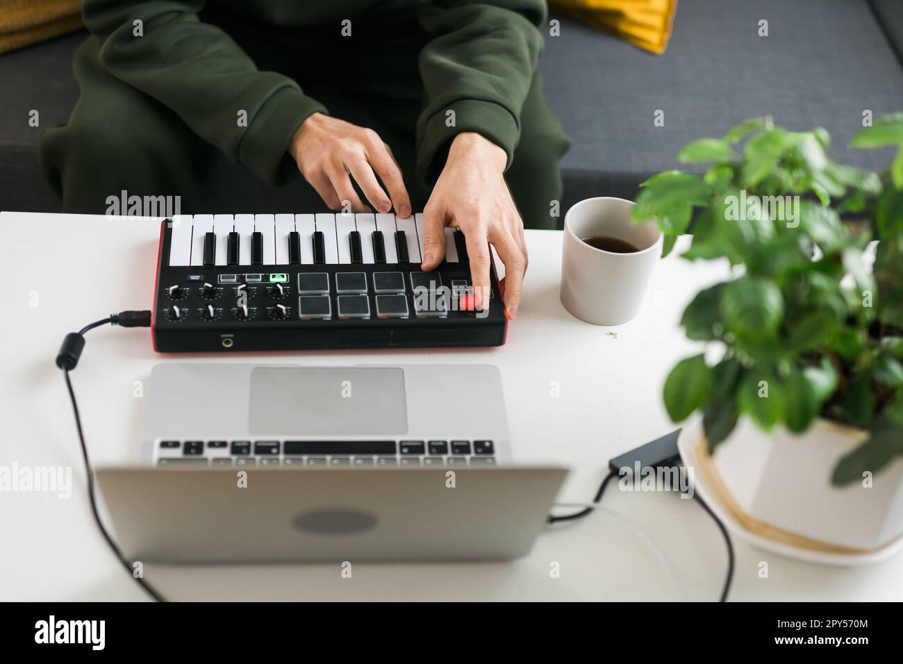 Top view of music producer or arranger using laptop and midi keyboard and other audio equipment to create music at home studio. Beat making and arranging audio content and composing song concept Stock Photo