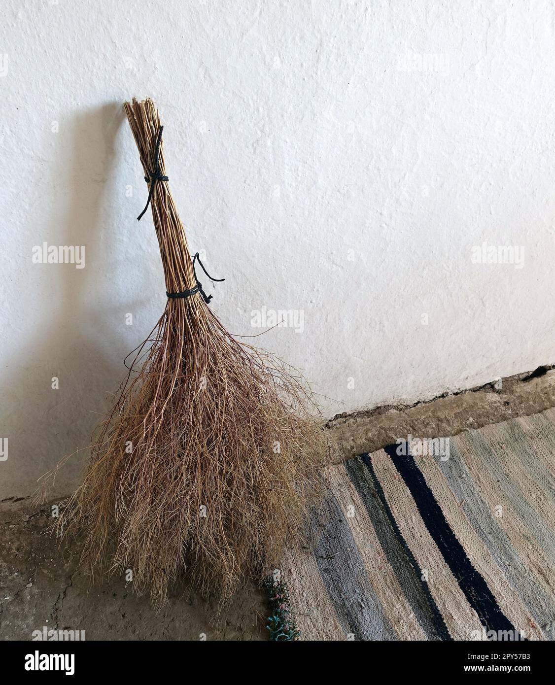 hand woven classic carpet and handmade grass broom, classic village household items Stock Photo