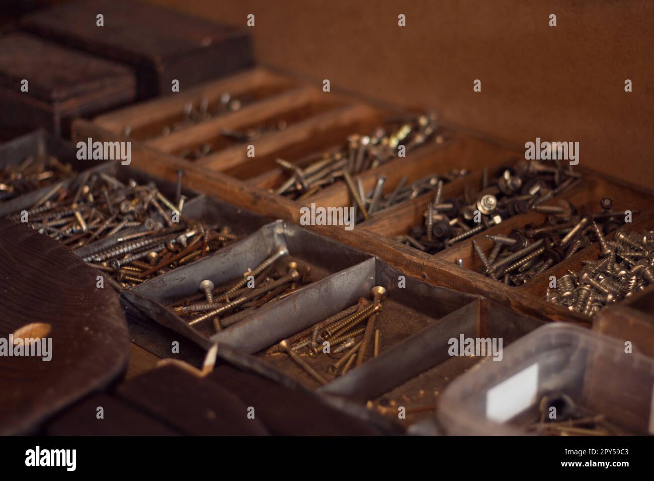 Old wooden toolbox with iron nails, screws, bolts and nuts. Storage of construction supplies in workshop. Male work box. Stock Photo