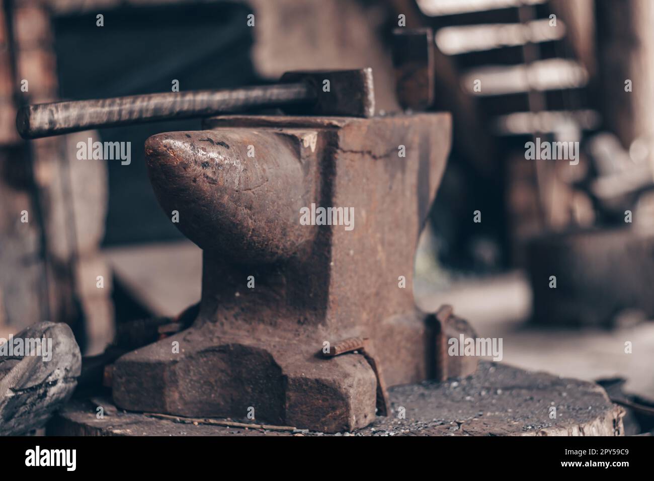 Process metal with hammer on anvil in forge. Strike iron outdoors in workshop. Metalworking, blacksmithing. Stock Photo