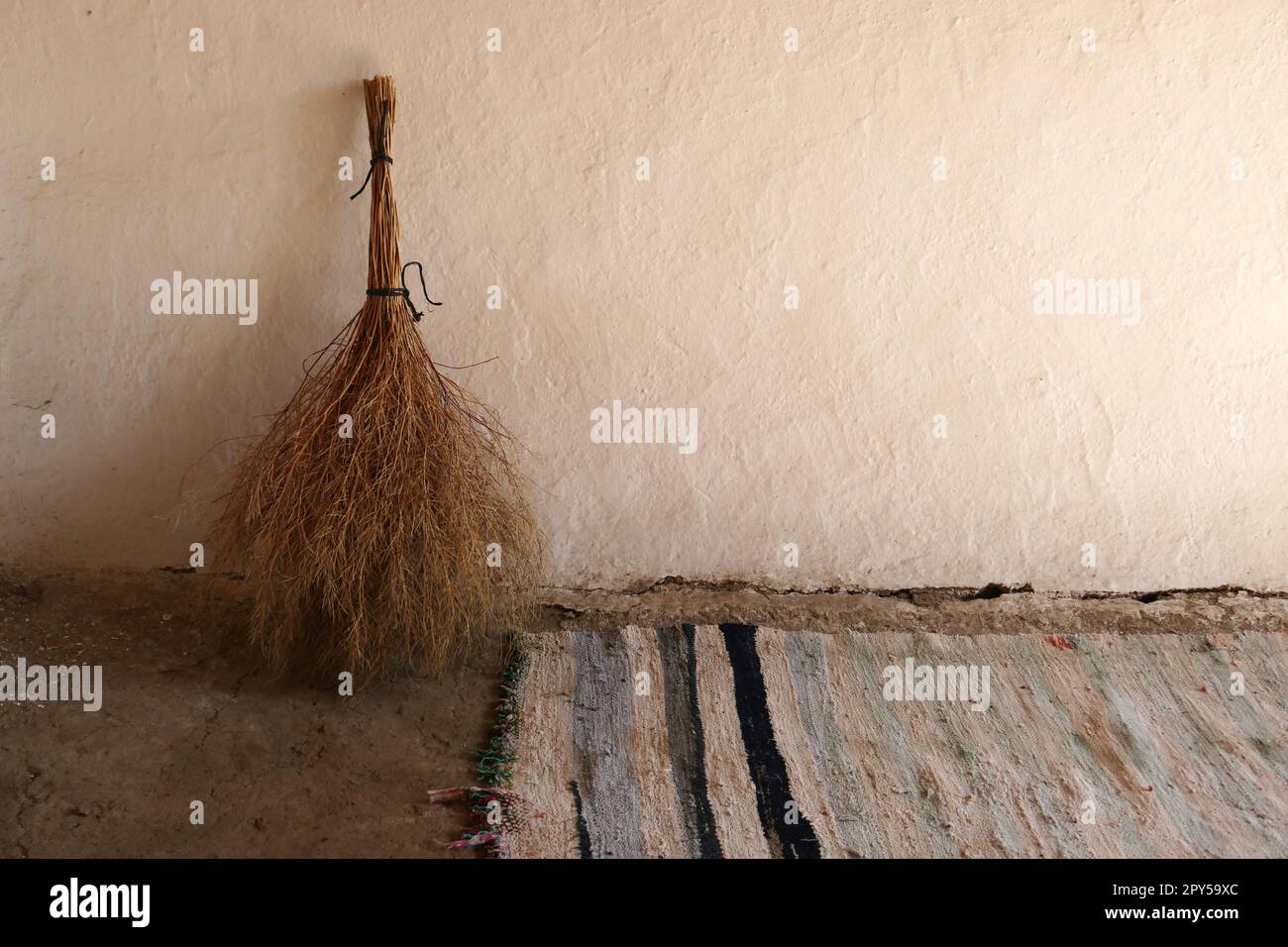 hand woven classic carpet and handmade grass broom, classic village household items Stock Photo