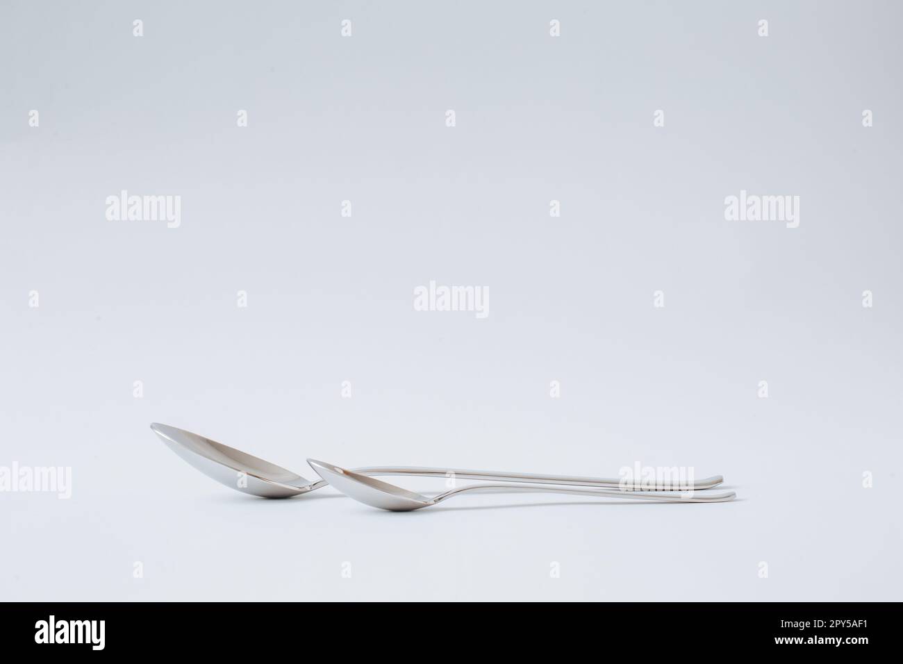 Stainless steel spoon, teaspoon laying on white background, kitchenware, copy space, close-up. Stock Photo