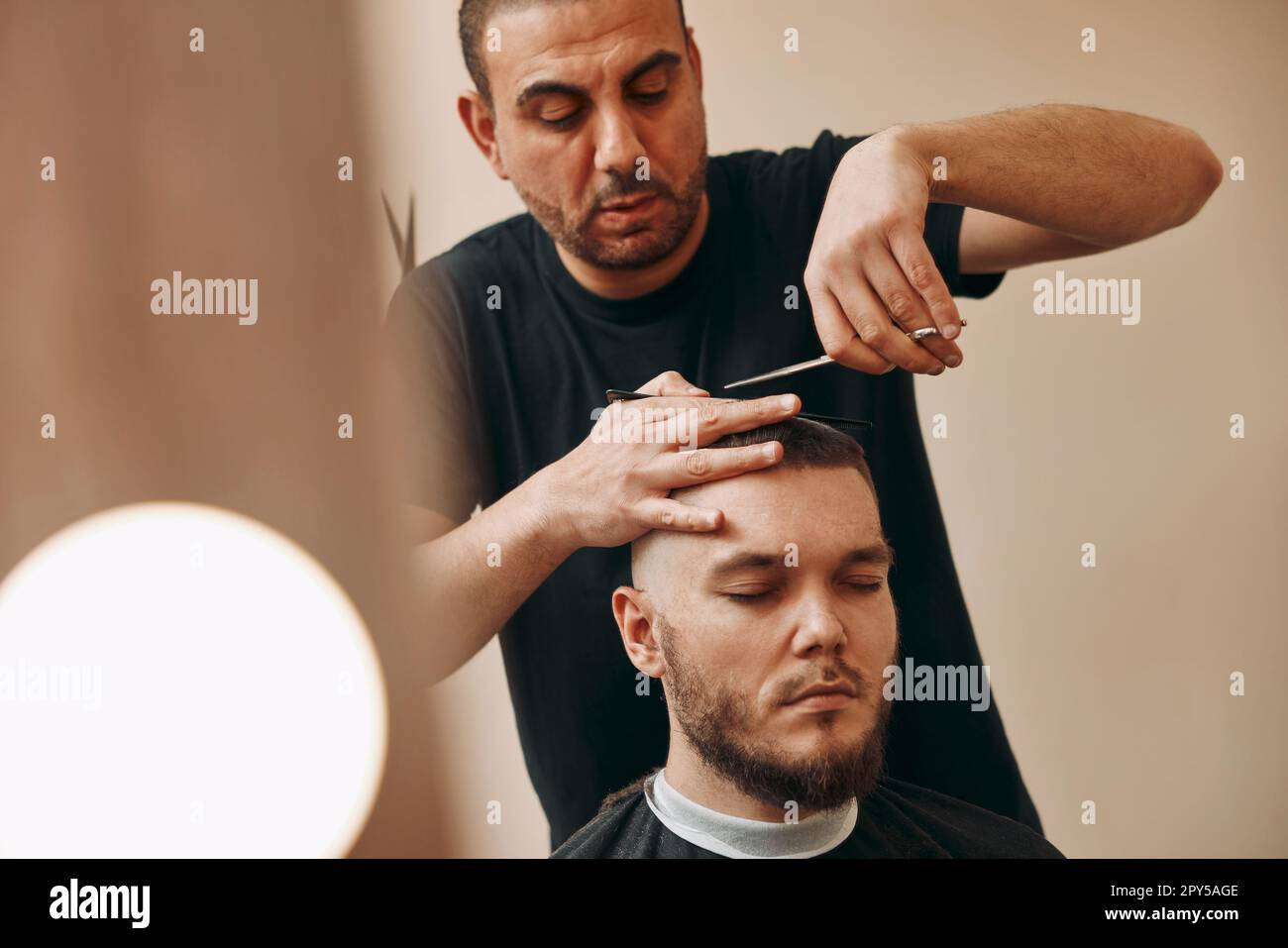 hairdresser does hairstyle with scissors in barber shop Stock Photo