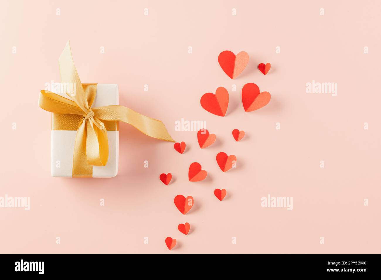 Top view flat lay of paper hearts and gift box on pastel pink ...
