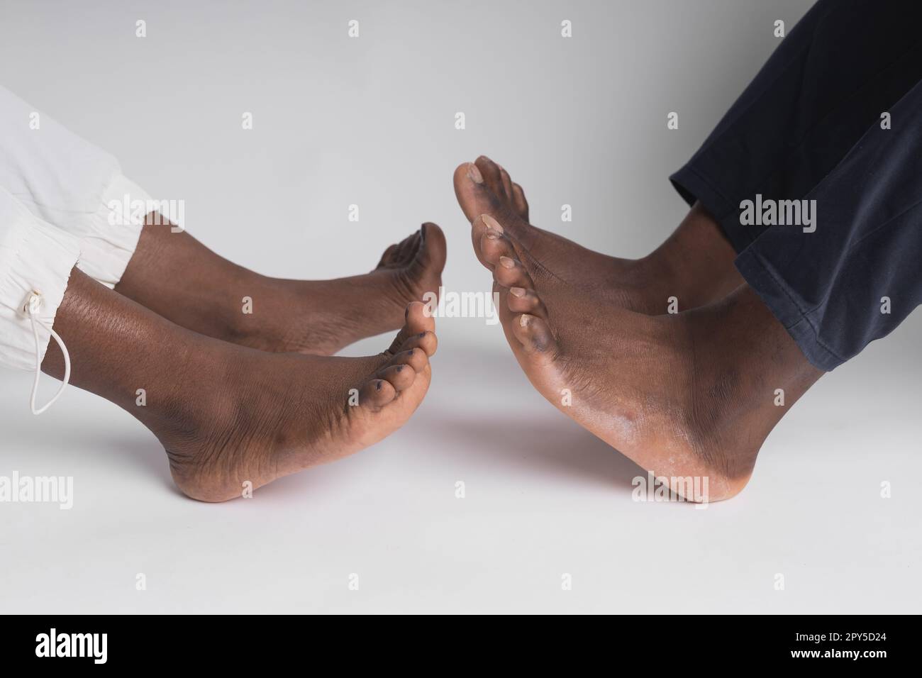 Close up African American man and woman legs touching holding together isolated on white background for love and healing concept Stock Photo