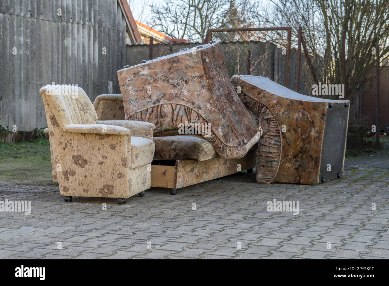Old armchairs and sofa stand outdoors on the street to be disposed of Stock Photo
