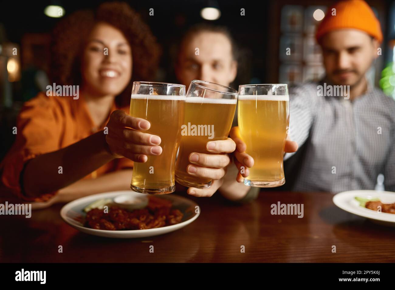 Group of young people smiling at camera and clinking glasses Stock Photo