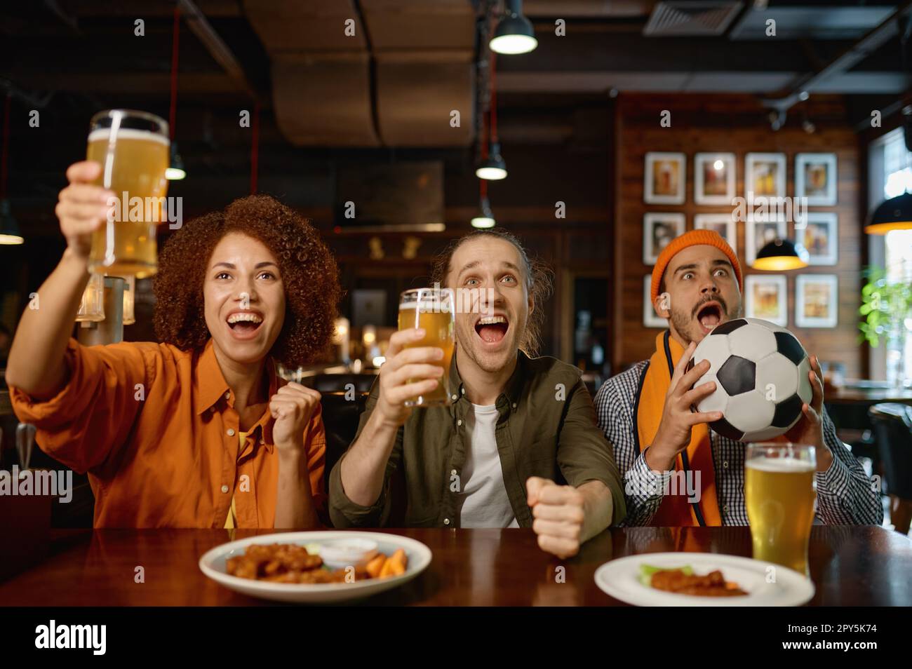 Group of sports fan celebrating goal for team and cheering at sports bar Stock Photo